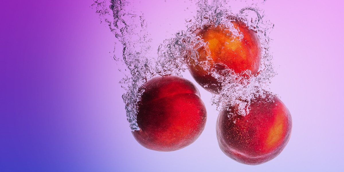 Image d'ambiance avec trois pêches dans une éclaboussure d'eau sur fond violet, saveur pêche, 20 mg.