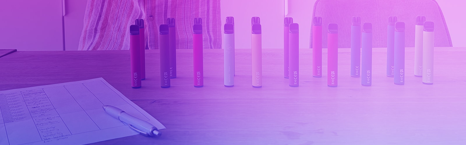 Plusieurs cigarettes électroniques jetables de différentes couleurs sur une table en bois devant un rideau, 20 mg