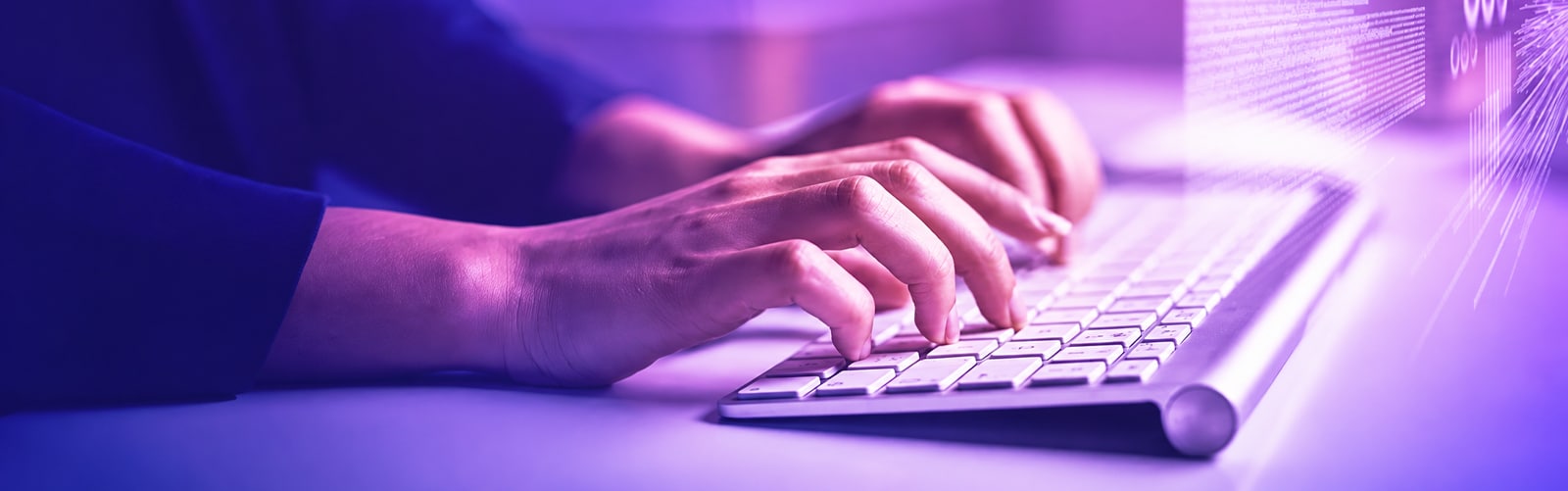 Nahaufnahme von Händen, die auf einer weißen Computer-Tastatur im violetten Licht tippen